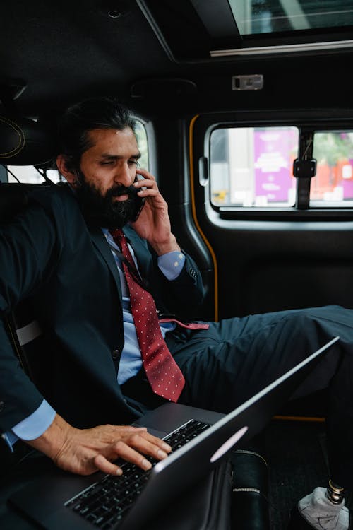 Businessman talking on Phone while looking at his Laptop 