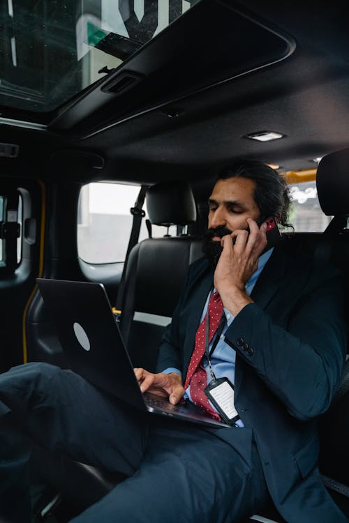 Free Businessman talking on Phone while using his Laptop  Stock Photo