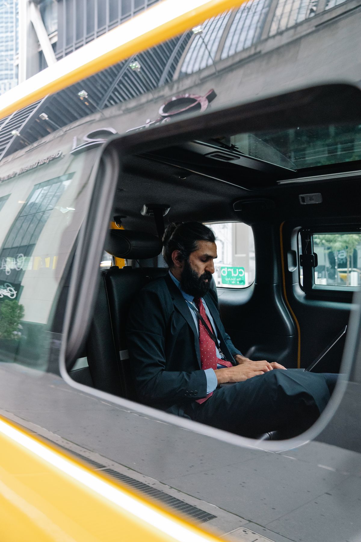 A working professional using a laptop during a daily cab commute