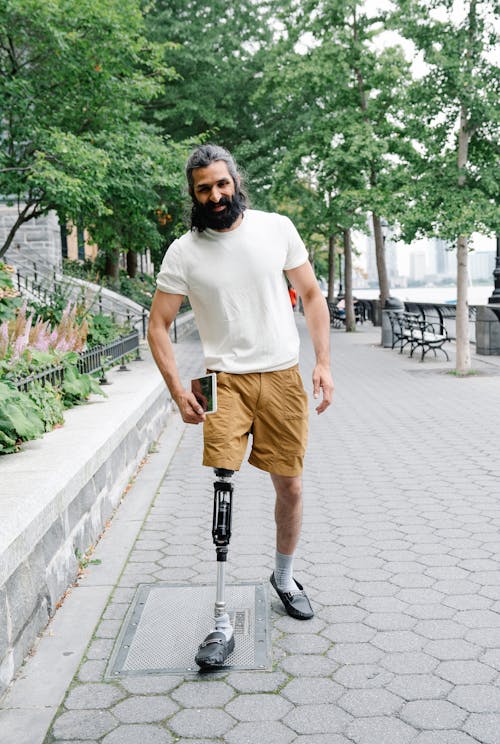Smiling Man with Prosthetic Limbs walking on a Pavement 