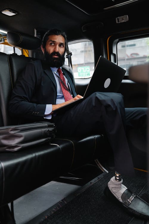 Man seated inside a Car with Laptop on his Lap