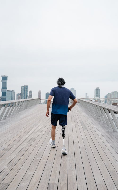 Man with Prosthetic Limb walking on a Wooden Footbridge 