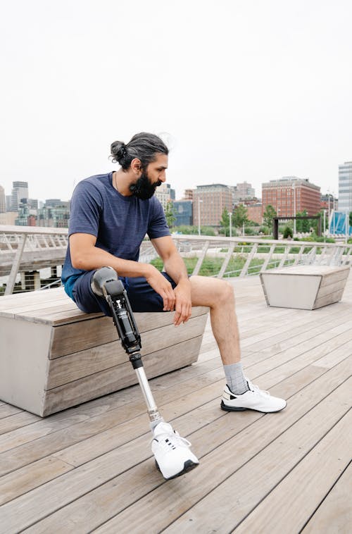 Free Man with Prosthetic Limb seated on a Wooden Bench  Stock Photo