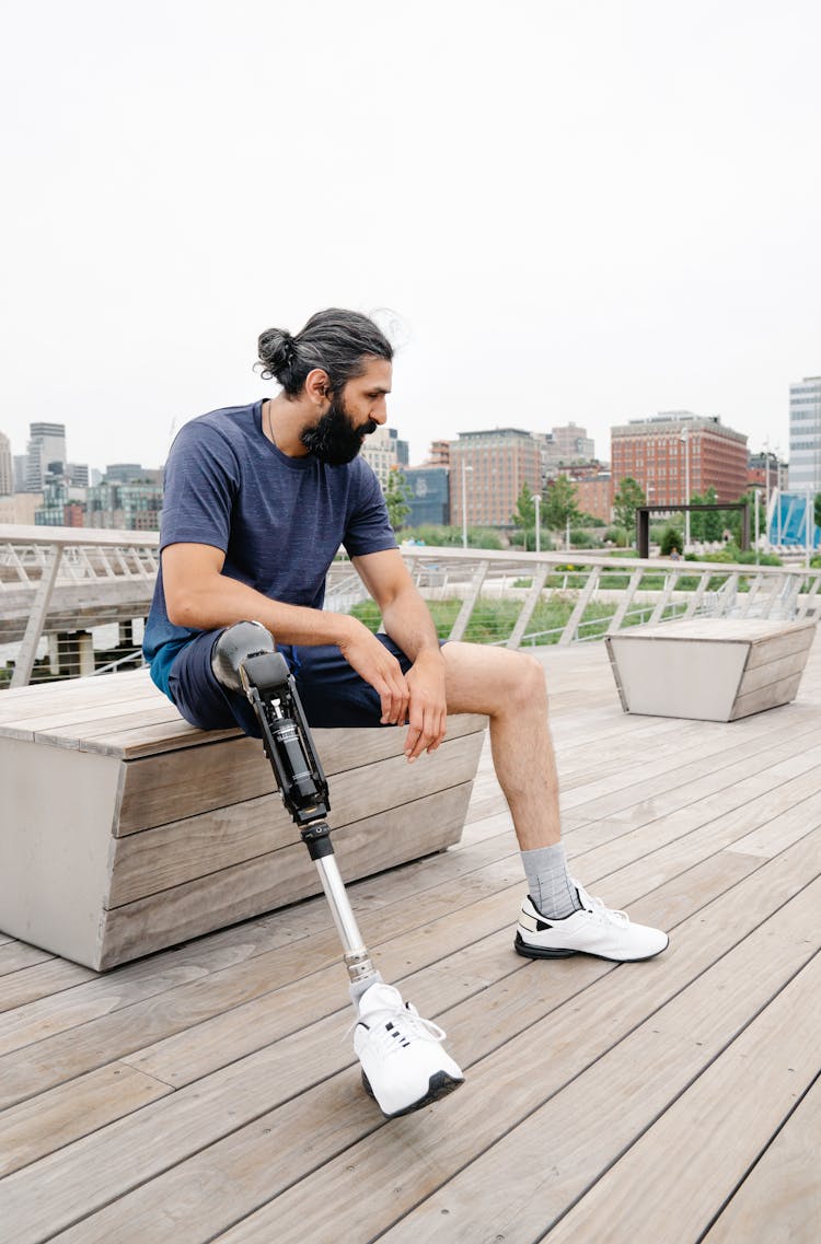 Man With Prosthetic Limb Seated On A Wooden Bench 