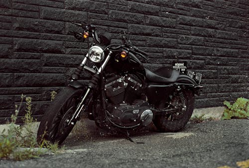 Free Black and Silver Cruiser Motorcycle Parked Beside Brown Brick Wall Stock Photo