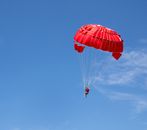 Person in Red Parachute in Mid Air