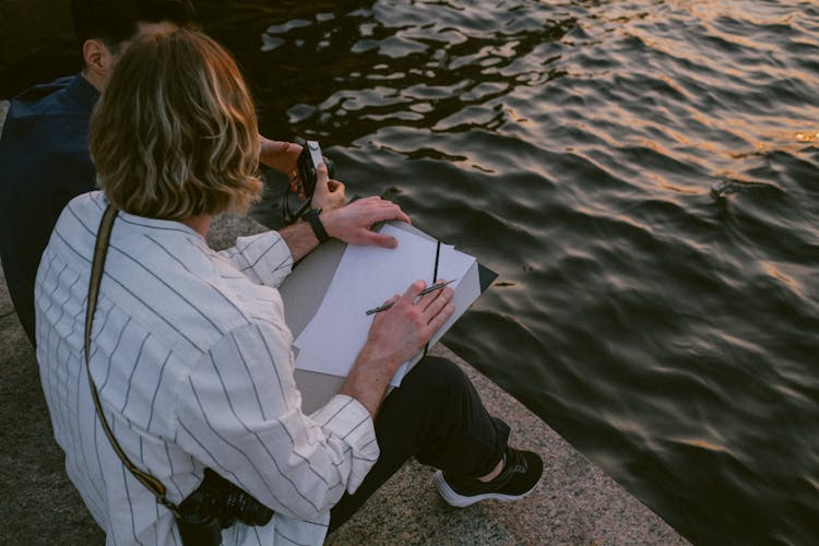 Men Sitting By Water