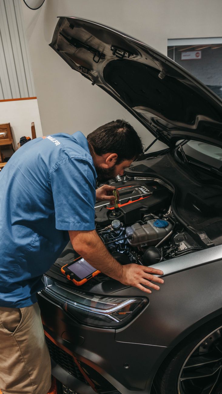 Mechanic examining a car's engine under an open hood