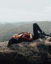 Girl in chequered pattern shirt lying on rock