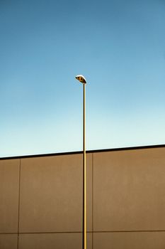 A tall street lamp rises against a clear blue sky, emphasizing minimalist architecture.