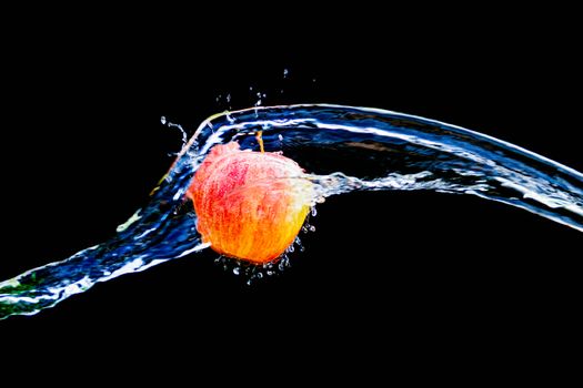 A vibrant apple submerged in water splash on a black background.