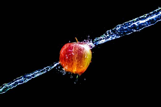 Dynamic image of a red apple splashing through water against a black backdrop, showcasing motion and freshness.