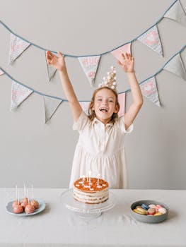 A cheerful child celebrating a birthday with cake and decorations indoors.