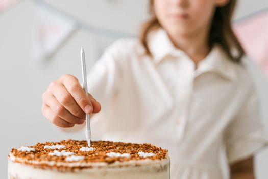A child in a white shirt places a candle on a birthday cake, ready for a celebration.