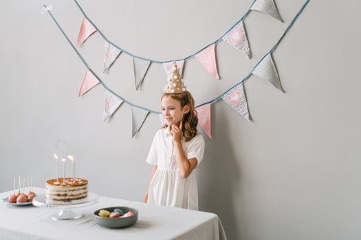 A young girl enjoys her birthday party indoors with cake and decorations.