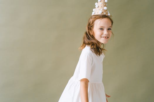 A happy girl wearing a festive party hat, smiling in a studio setting.