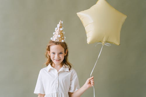 A Young Girl Holding a Star Shaped Balloon