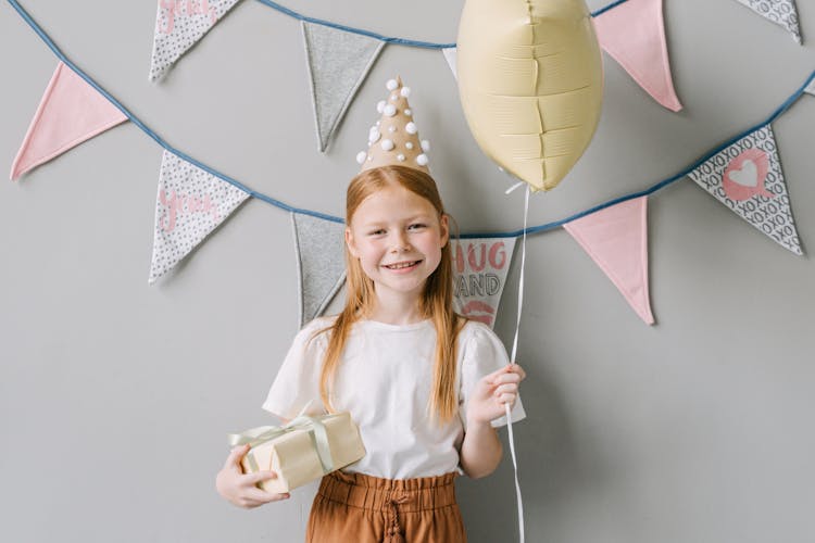 Photograph Of A Girl Holding A Gift And A Balloon