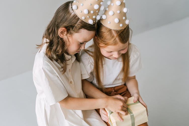 Girls Wearing Party Hats Opening A Gift