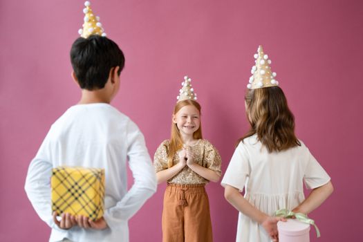Joyful children celebrating a birthday with hats and gifts in a lively indoor setting.