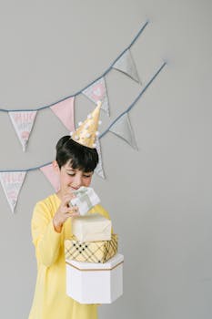 A happy child opening gifts at a birthday party, wearing a festive hat and smiling.