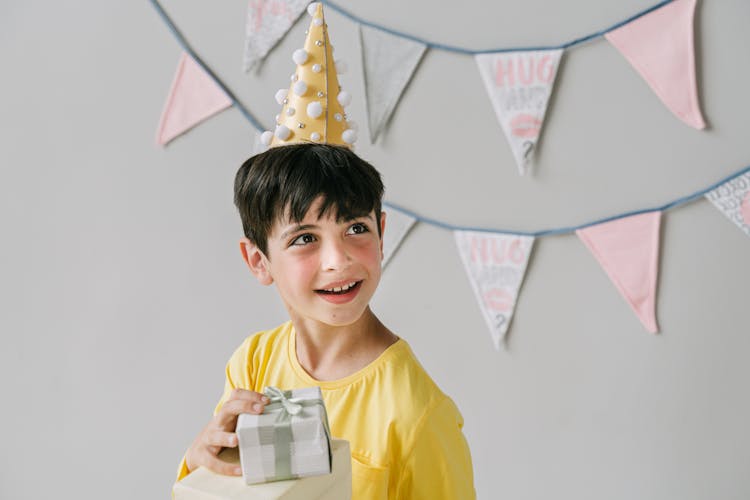 Close-Up Shot Of A Boy Smiling While Holding A Birthday Gift