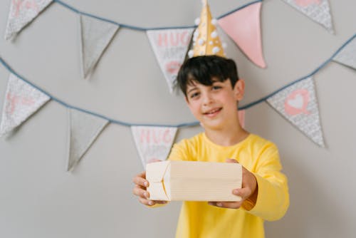 A Boy in a Yellow Shirt Holding a Birthday Present