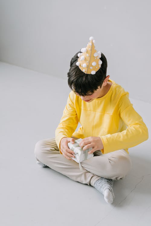 Free A Boy in Yellow Long Sleeves Opening a Gift Stock Photo