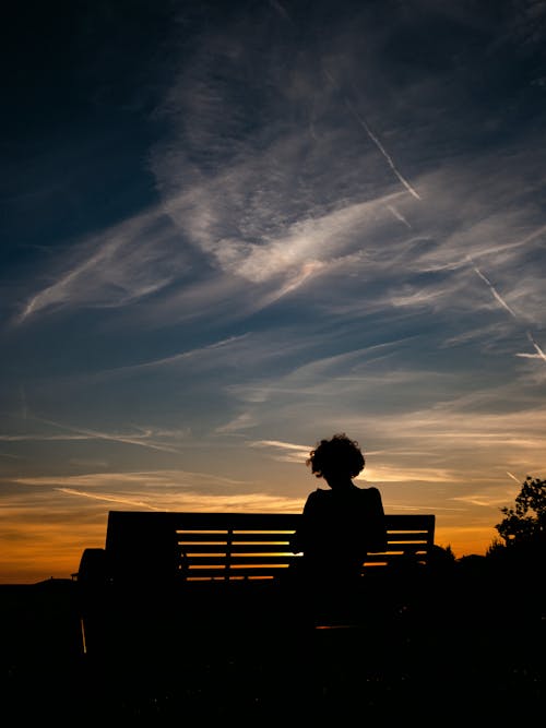 Silhouette of Woman Sitting on Bench on Sunset