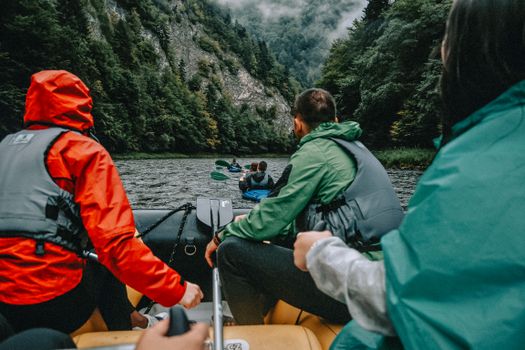 A group enjoying river rafting surrounded by lush green mountains.