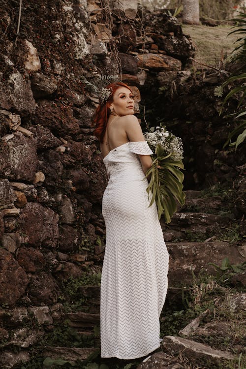 Woman in Off Shoulder White Dress Holding Bouquet of Flowers