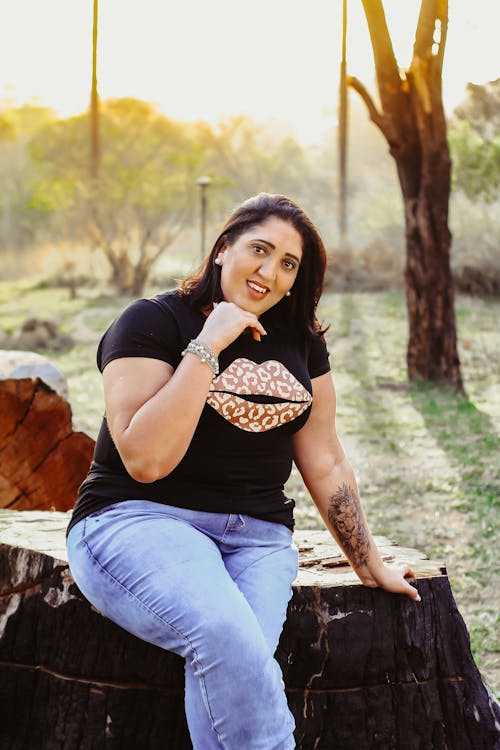 Woman Sitting on Wood Stump in Park