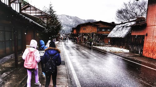 Three People in Hoodie Jackets Walking Beside Road