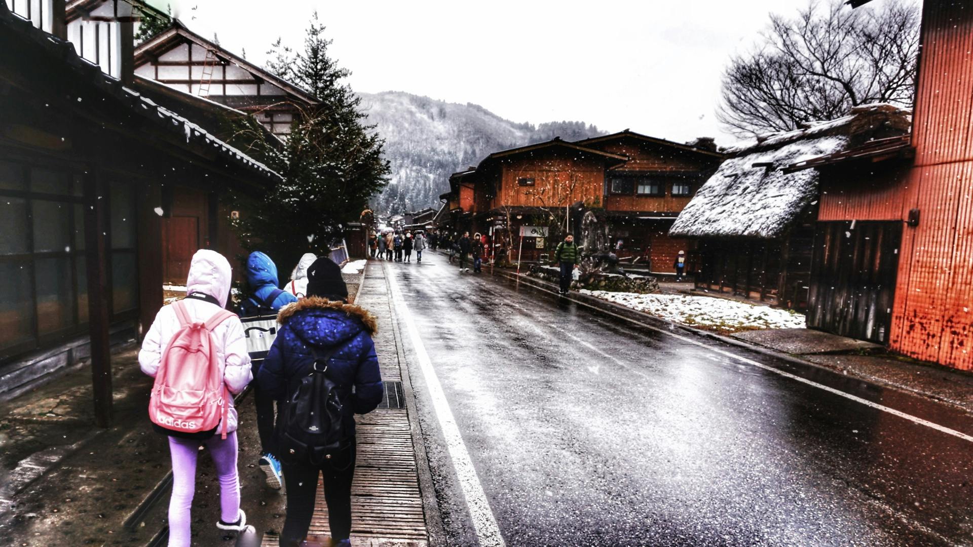 A group of people walking in Nagawa, Japan during winter, capturing traditional architecture.