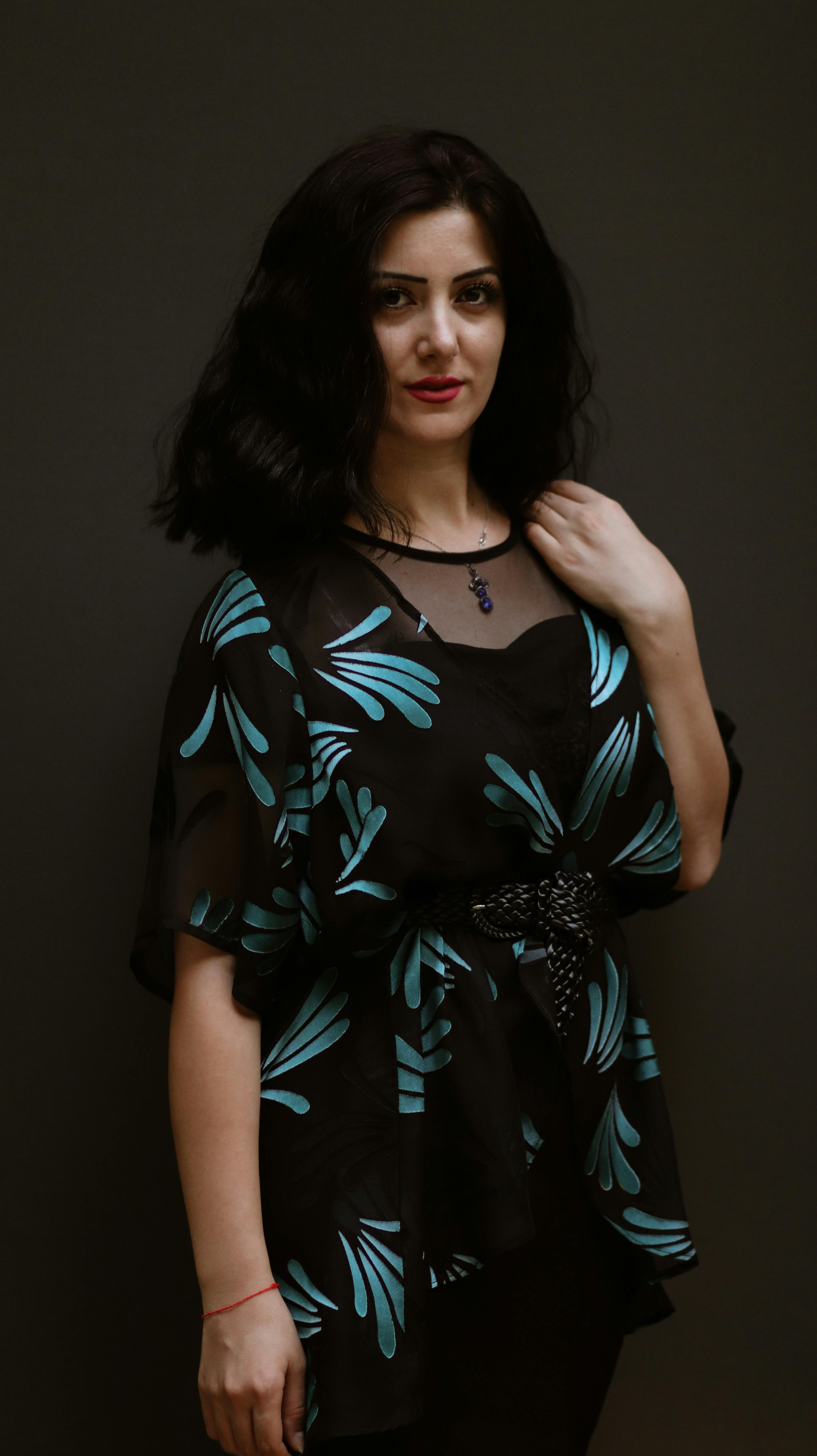 Portrait of a woman in a stylish printed dress with dark background, exuding elegance and confidence.