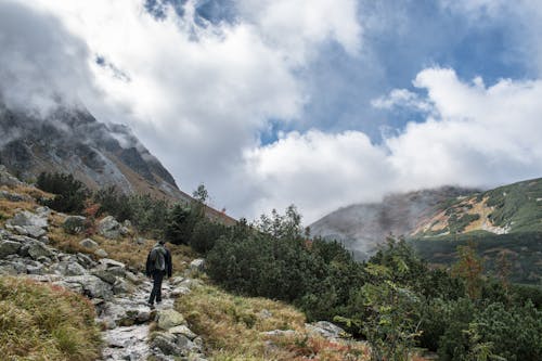 Man Walking on Rocky Pathway Near Mountain