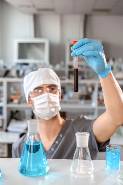 Free A scientist in protective gear examines a test tube in a research laboratory setting. Stock Photo