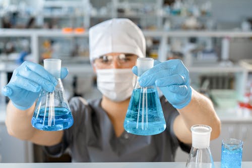 Free A Man Holding Colored Liquid on Erlenmeyer Flasks Stock Photo