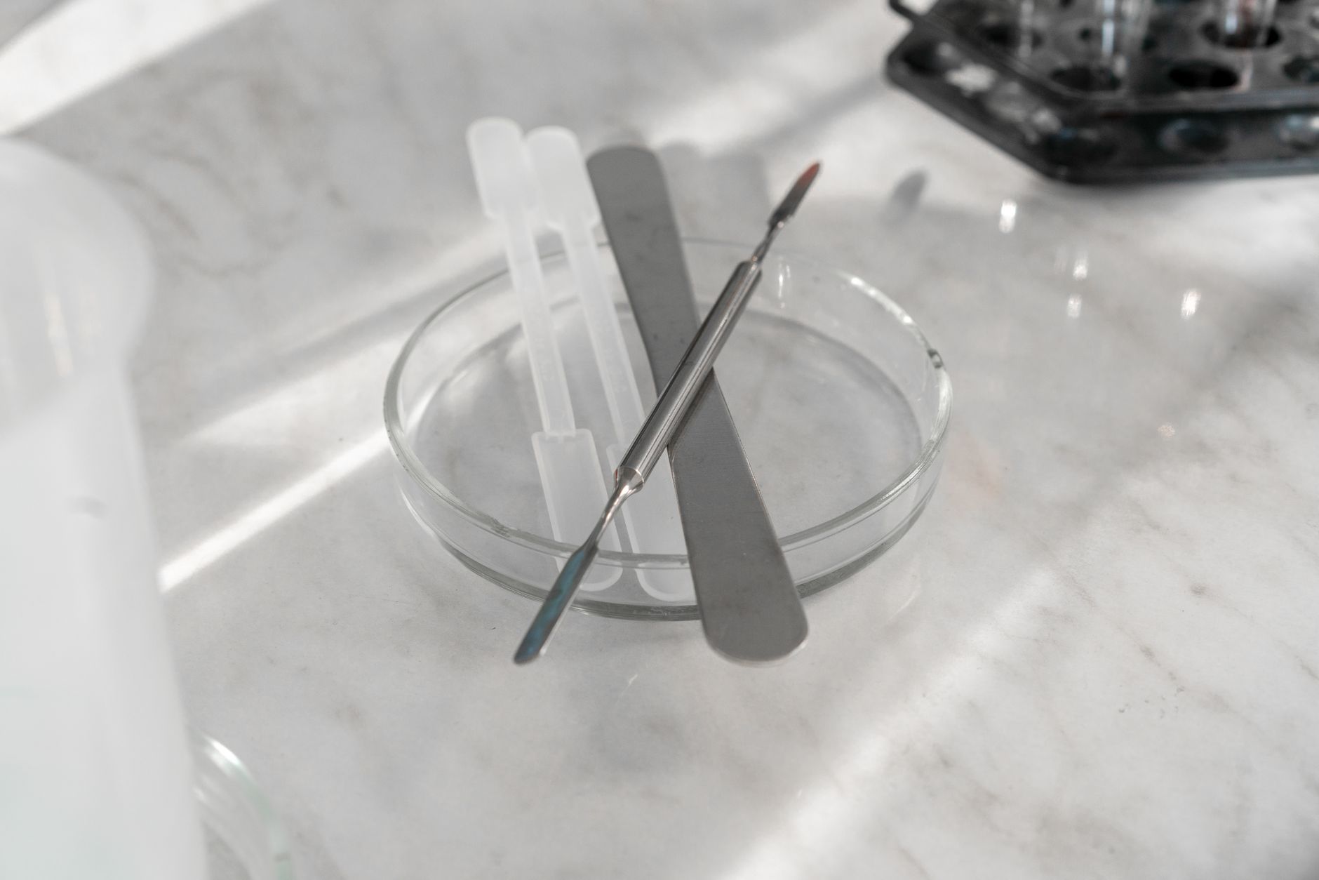 A detailed close-up of various laboratory tools placed on a glass plate, ideal for scientific research themes.