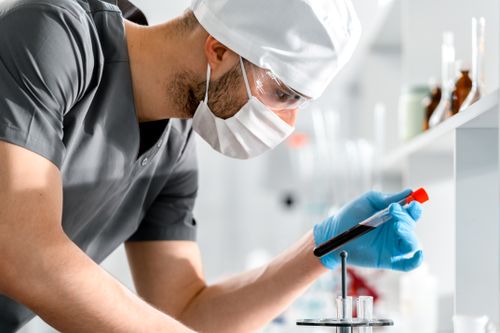 Free A researcher in a lab coat carefully examines a test tube, symbolizing scientific discovery and research. Stock Photo
