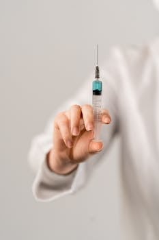 Detailed image of a hand holding a vaccine syringe, highlighting healthcare and medicine concepts.