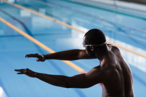 Free Male swimmer stretching before practice at indoor pool, back view. Stock Photo