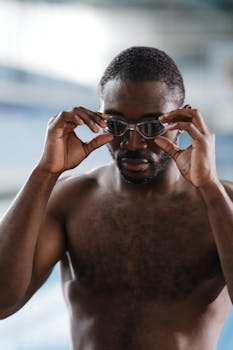 Determined swimmer adjusting goggles before diving into practice session.