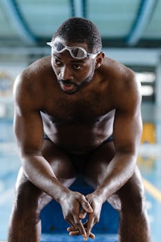 Determined athlete taking a moment of reflection by the poolside.