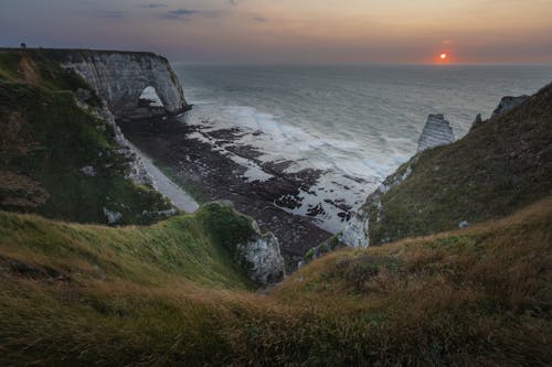 Free Mountain Cliff with Rocky Coast Near Body of Water during Sunset Stock Photo