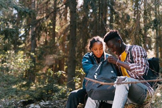 A young couple examining their backpack in a lush forest setting, enjoying outdoor exploration.
