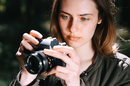 Photo of a Woman with Freckles Using a Black Camera