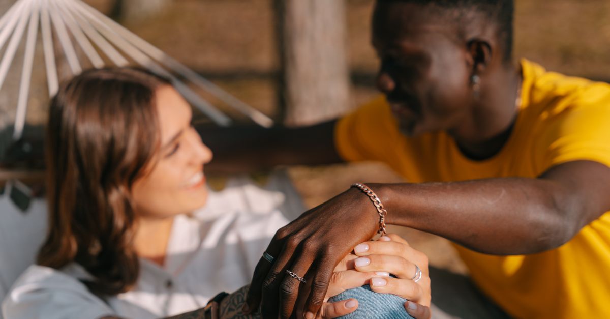 A joyful couple enjoying a sunny day together in a hammock, sharing a delightful moment outdoors.