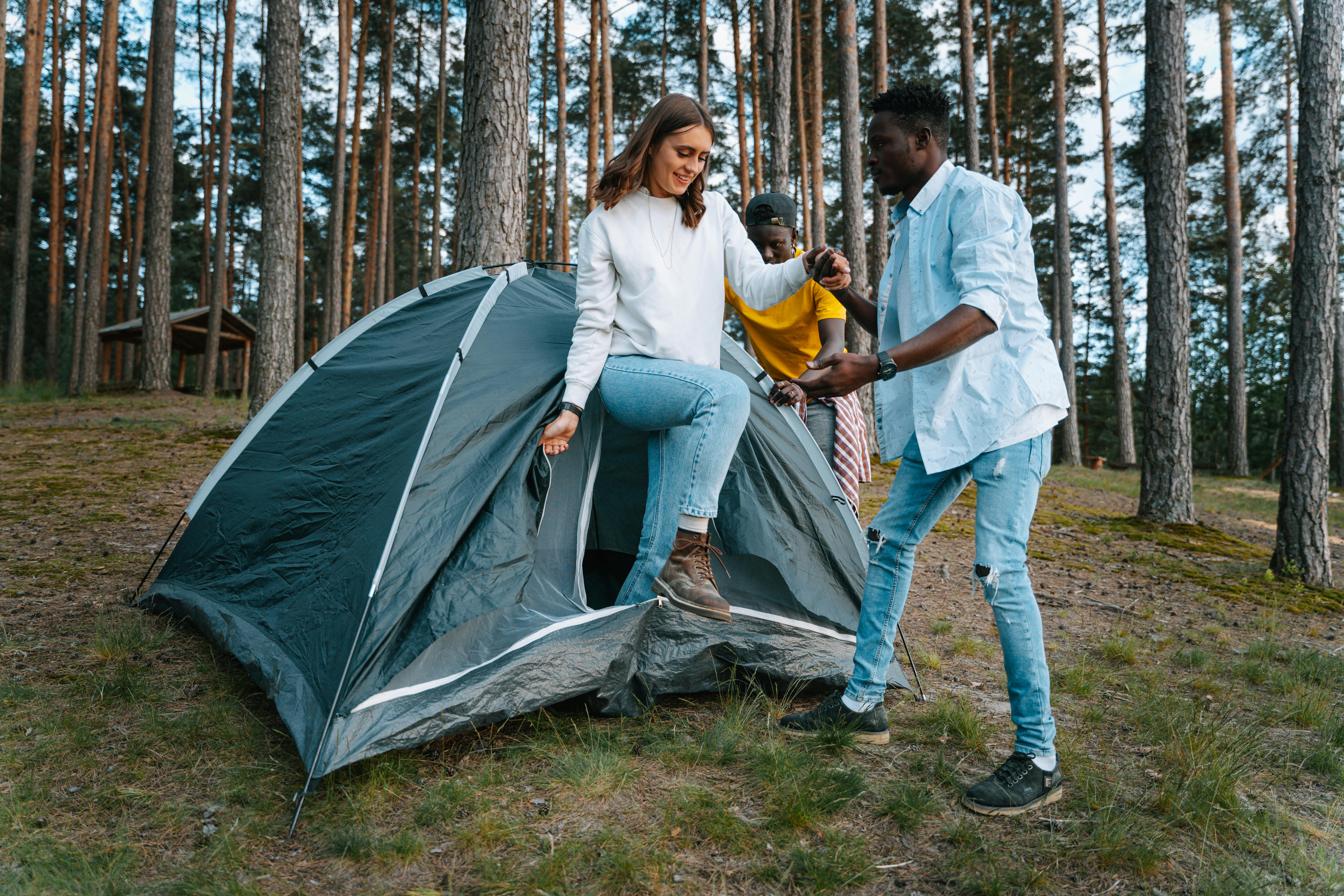 man helping woman to get out of tent