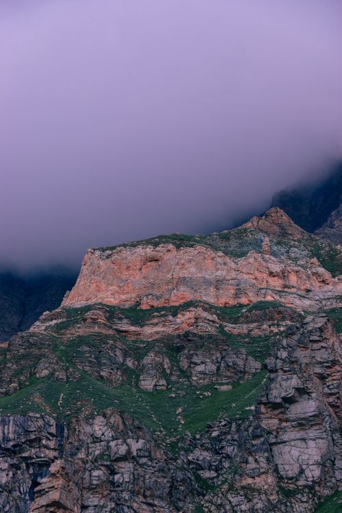 Free Mysterious rocky mountain landscape enveloped in fog under twilight. Captivating nature scene. Stock Photo